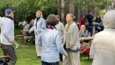 Eine Gruppe älterer Menschen steht im Park und unterhält sich.