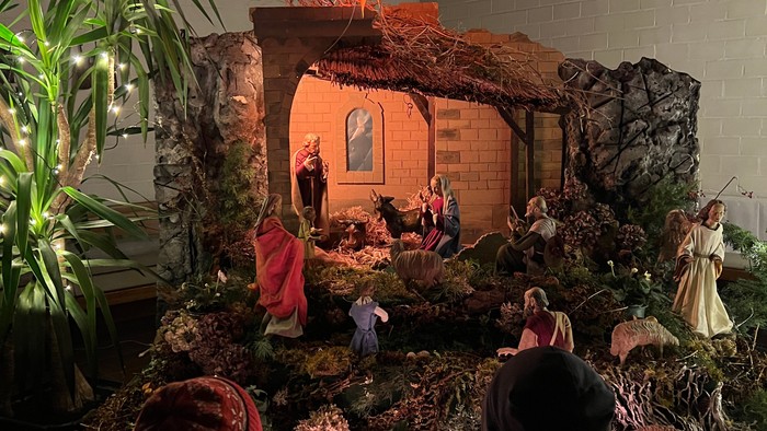 Krippe mit Figuren und Stern, zwei Personen schauen zu