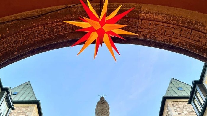 Bunter Stern über Kirche, Statue im Vordergrund