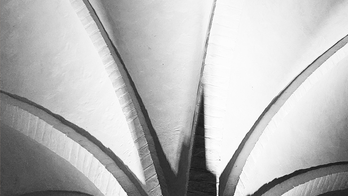 Sort-hvid fotografi af en moderne arkitekturstruktur med buede linjer, med navnene *