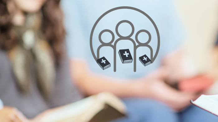 En gruppe af mennesker sidder ved et bord og diskuterer, mens de holder penner og papir.