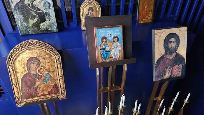 Billedet viser religiøse ikoner og lysstake i en kirke.