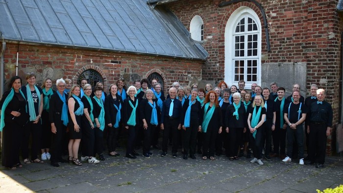 Eine Gruppe von Menschen in schwarzen und blauen Outfits posiert vor einem Ziegelgebäude.