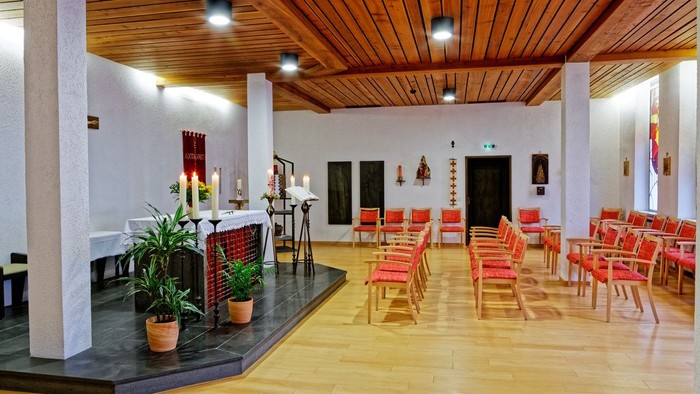 Großer Raum mit Holzboden, roten Stühlen und Topfpflanzen