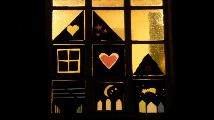 Ein Fenster mit Buntglas, das Herzen, Sterne und einen Mondsichel zeigt.