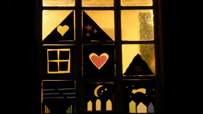 Ein Fenster mit Buntglas, das Herzen, Sterne und einen Mondsichel zeigt.