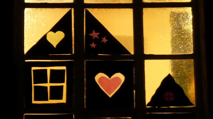 Ein Fenster mit Buntglas, das Herzen, Sterne und einen Mondsichel zeigt.