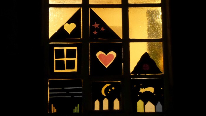 Ein Fenster mit Buntglas, das Herzen, Sterne und einen Mondsichel zeigt.