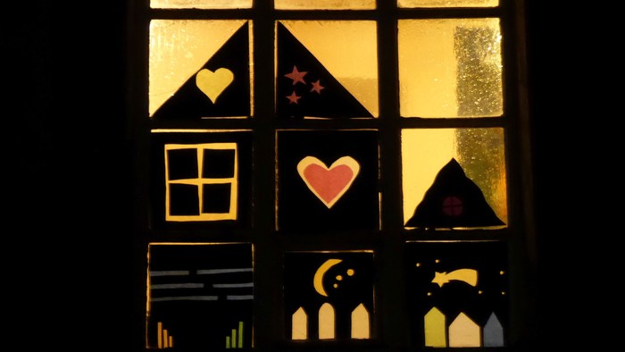 Ein Fenster mit Buntglas, das Herzen, Sterne und einen Mondsichel zeigt.