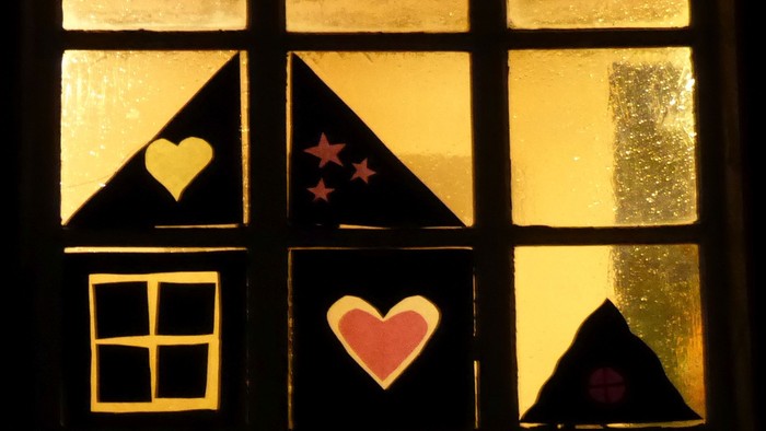 Ein Fenster mit Buntglas, das Herzen, Sterne und einen Mondsichel zeigt.