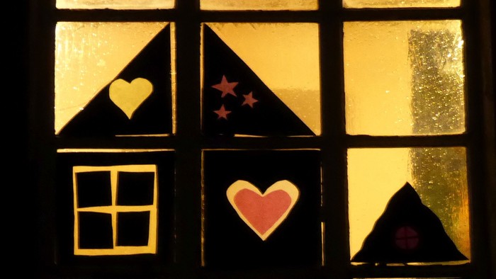 Ein Fenster mit Buntglas, das Herzen, Sterne und einen Mondsichel zeigt.