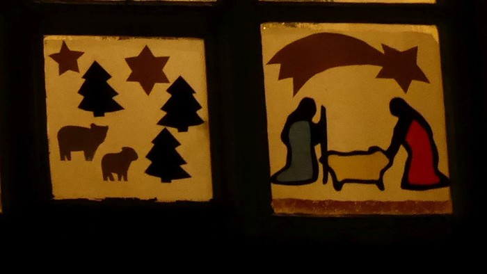 Fenster mit beleuchtetem Adventskalender, das Daten und festliche Szenen zeigt