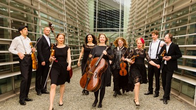 Musikere poser med instrumenter i moderne bygning.