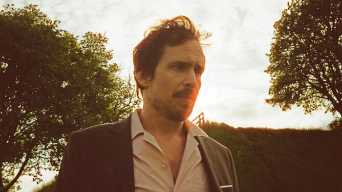 Mand i jakkesæt står udenfor og kigger op.