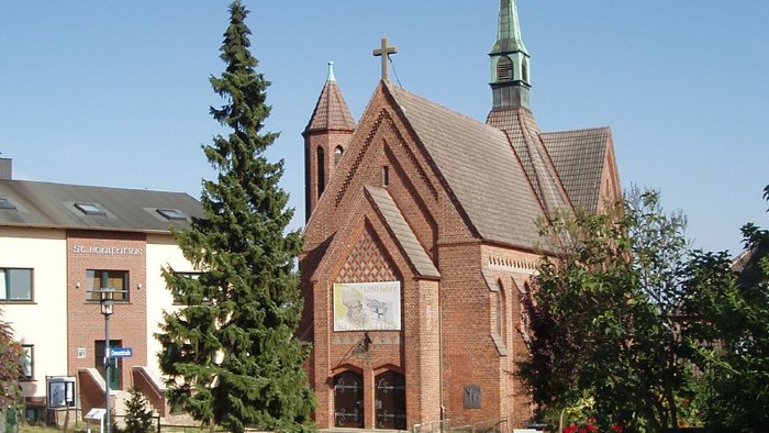 Kirchengelände mit Kopfsteinpflasterweg und Bäumen