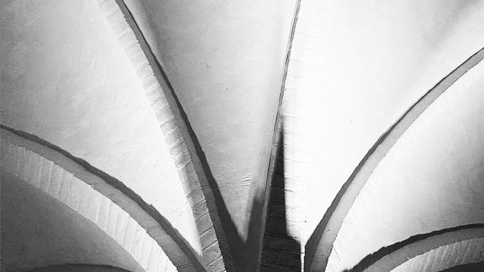 Sort-hvid fotografi af en moderne arkitekturstruktur med buede linjer, med navnene *