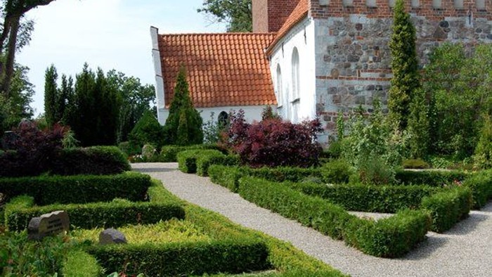 En smuk have med en stenkirke i baggrunden