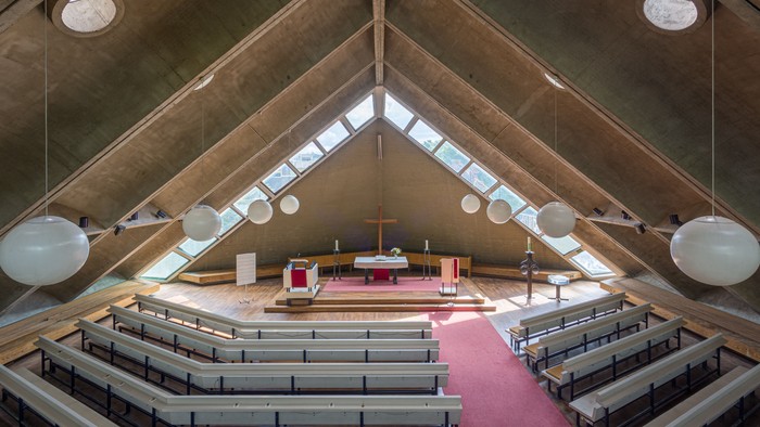 Moderne Kirche mit hölzernen Sitzreihen und großen runden Fenstern.