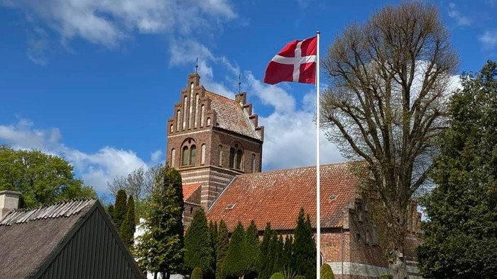 Flag på kirkegård med kirke og træer