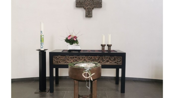Ein Altar mit Kreuz, Kerzen und Blumen in einem Raum