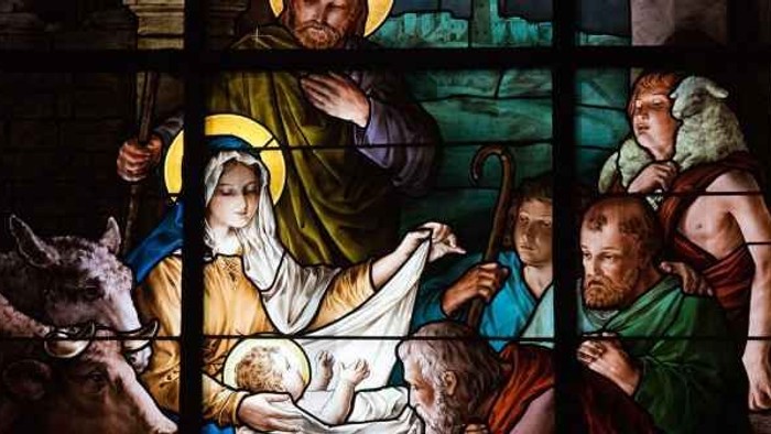 Stained glass skildring af Jesus' fødsel med Maria og Josef samt dyr og andet.