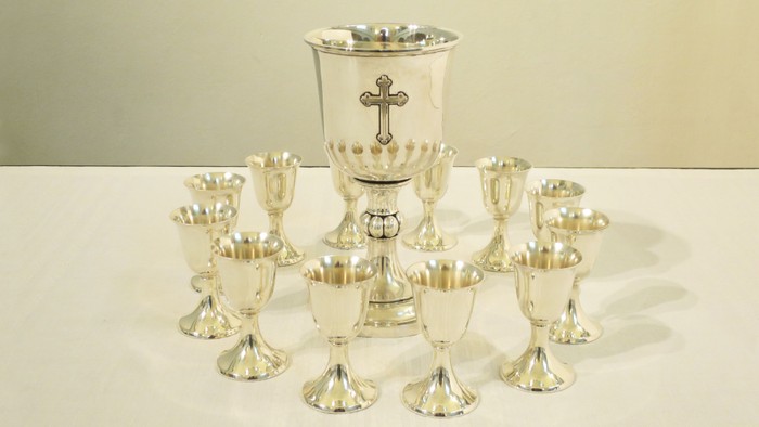 Silberne Kelch und zwölf Kelchchen auf weißem Tisch