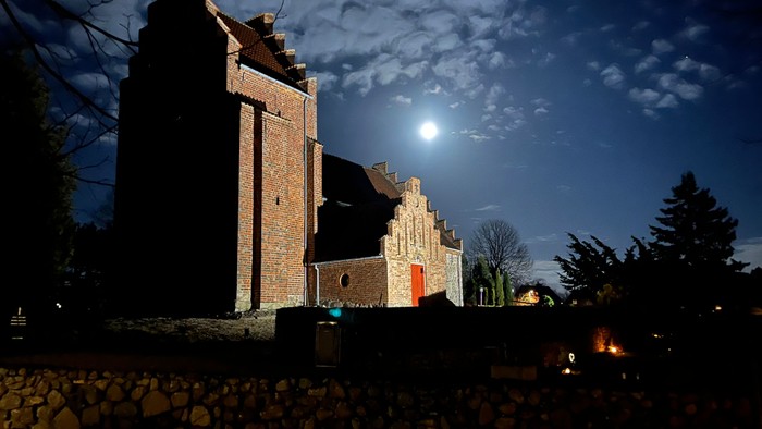 Gamle slotsruiner i måneskin med en forsamling omkring.