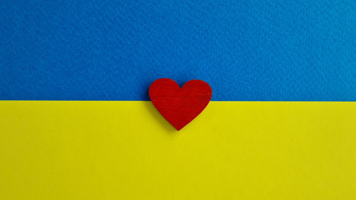 Et rødt hjerte placeret på en blå og gul baggrund, der ligner det ukrainske flag.