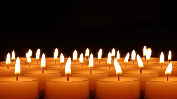 Eine Reihe brennender Kerzen vor dunklem Hintergrund