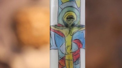 Ein buntes Glasfenster mit einer Figur und einem roten Symbol.