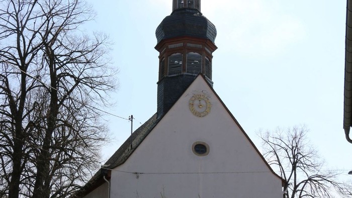 Kleine weiße Kirche mit schwarzem Turm und Kreuz auf dem Dach.