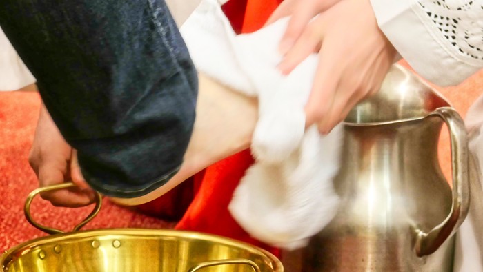 Hände eines Priesters trocknen einen nakten Fuß