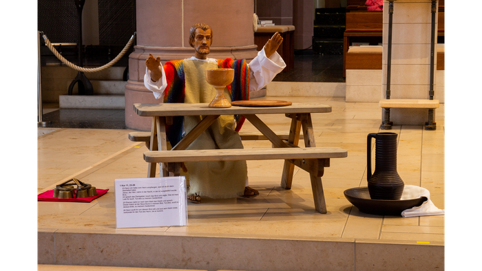 Eine Miniaturfigur sitzt an einem Picknicktisch in einem Schaufenster.