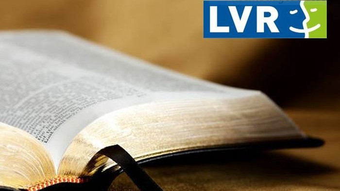 Ein aufgeschlagenes Buch mit Lesebrille auf einer Holzoberfläche