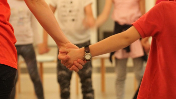 En gruppe børn holder hånd og danser i en cirkel.