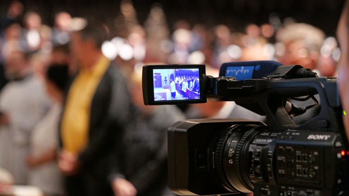 Eine Kamera filmt eine Menschenmenge.