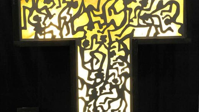 Ein kreuzförmiges Buntglasfenster mit aufwendigen Verzierungen, das prominent ausgestellt ist.