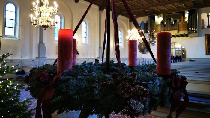 Indre del af kirke med juldekorationer og lys.