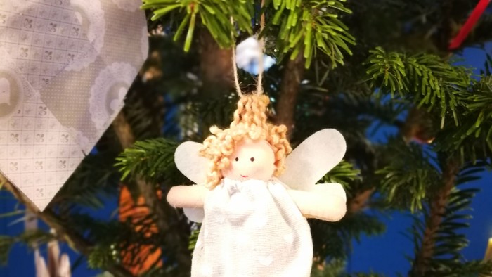 En lille engelornament hænger på en juletree