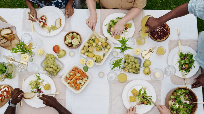Eine vielfältige Gruppe genießt gemeinsam eine bunte, gesunde Mahlzeit an einem Gemeinschaftstisch.