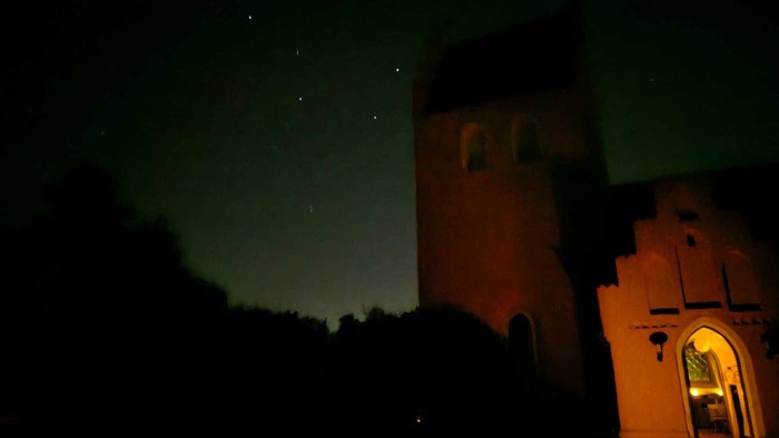 Et slot under en grøn nattehimmel med stjerner.