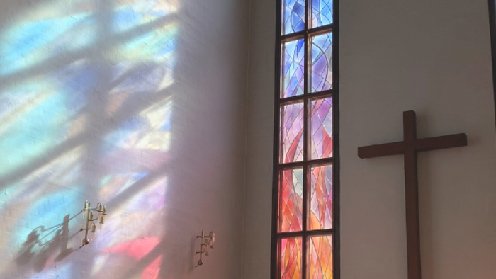 Farverige vinduesglas i kirke med kors og skygger