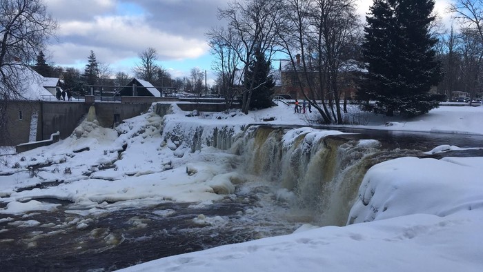 Schneebedeckte Landschaft mit Wasserfall und Brücke