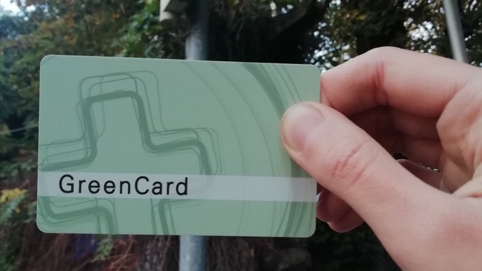 Hand hält GreenCard vor grüner Ampel
