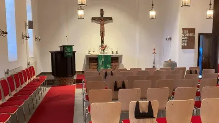 Leere Kirchenbankreihen vor Altar und Kruzifix