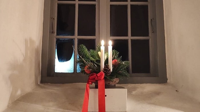 Vindue med tændte stearinlys og julepynt.