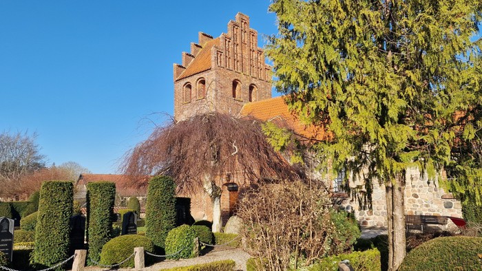 Et slot med høje murer og en stor træ i forgrunden