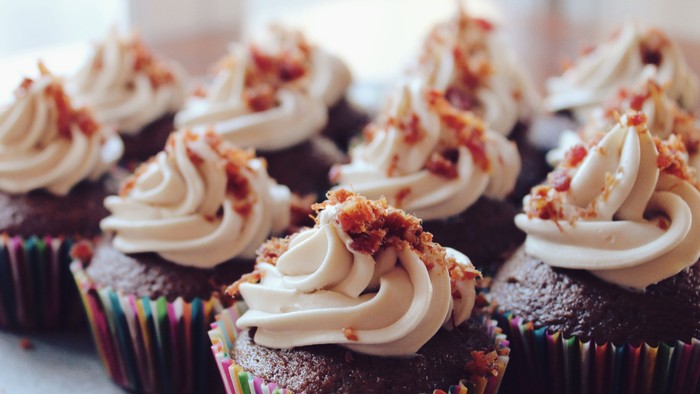 Chocolate cupcakes with frosting and bacon bits on top.