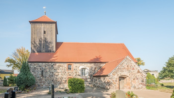 Altes Steinhaus mit rotem Dach und Turm unter blauem Himmel