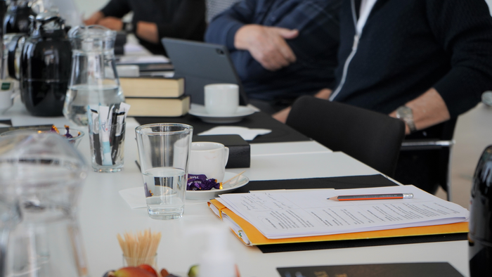 En gruppe af mennesker sidder ved et bord med notater og drikkevarer.